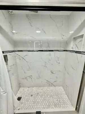a bathroom with a shower with white marble walls at Entire condo near Universal Studios in Orlando - Free Resort Access in Orlando
