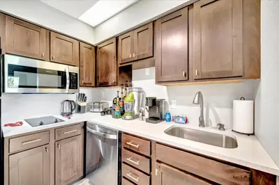 a kitchen with wooden cabinets and a sink at FREE Shuttle & 50 Dollars Disney Gift Card Disney Resort Condo in Orlando