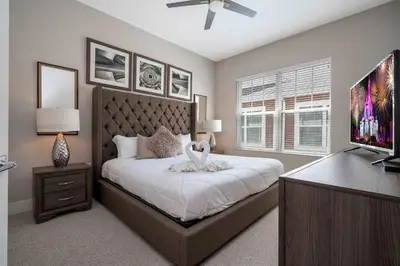 a bedroom with a large bed and a flat screen tv at Townhome 4Q c/ Temática Disney in Orlando