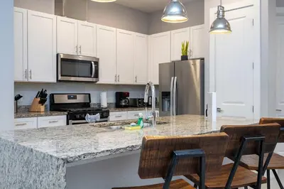 a kitchen with white cabinets and a granite counter top at Townhome 4Q c/ Temática Disney in Orlando