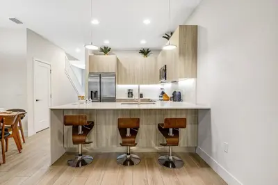 a kitchen with a counter with three bar stools at A Magical and Cozy Family Getaway 3BR Home Near Disney Studios in Orlando