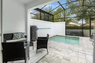 a patio with a pool and a table and chairs at A Magical and Cozy Family Getaway 3BR Home Near Disney Studios in Orlando