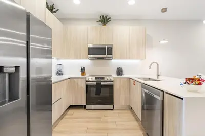 a kitchen with wooden cabinets and a stainless steel refrigerator at A Magical and Cozy Family Getaway 3BR Home Near Disney Studios in Orlando