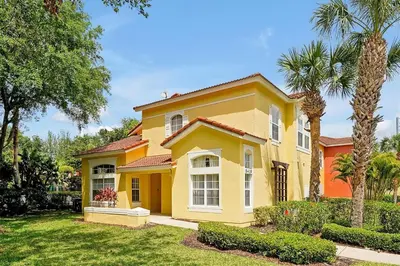 a yellow house with palm trees in a yard at 4BR Luxury Villa Private Pool & Slide Disney in Kissimmee