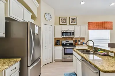 a kitchen with white cabinets and a stainless steel refrigerator at Casa aconchegante em Glenbrook perto da Disney in Orlando