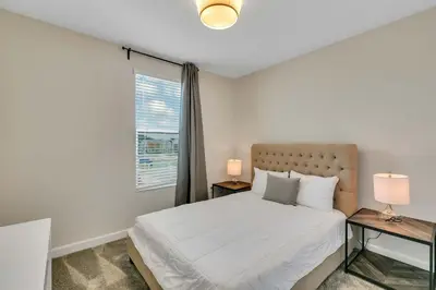 a bedroom with a bed with two lamps and a window at Classy 6BR Home with Private Pool in Kissimmee