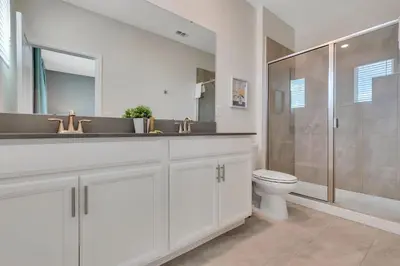a white bathroom with a toilet and a shower at Classy 6BR Home with Private Pool in Kissimmee