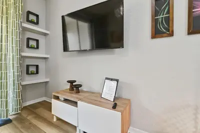 a living room with a television on a wall at Restpool vibes, Nest tree-ish Retreat- NxtDisney in Kissimmee