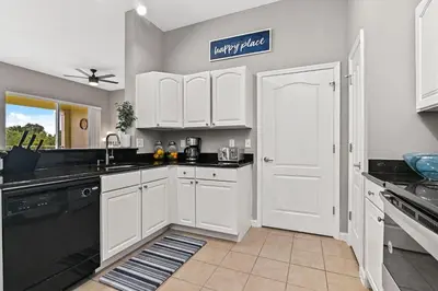 a kitchen with white cabinets and a black dishwasher at Sunset every single day ReserveView 4BRElevator in Kissimmee