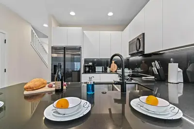 a kitchen with two plates and oranges on a counter at Look Out over Nature - Unique FRESH Corner Home in Orlando