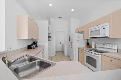 a kitchen with a stainless steel sink and white appliances at Windsor Palms 3BR FUN Retreat, Pool, Near Disney in Kissimmee