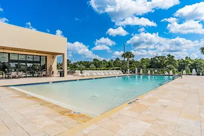 a large swimming pool in front of a building at Brand New Home with 4 En-Suites, near Disney in Kissimmee