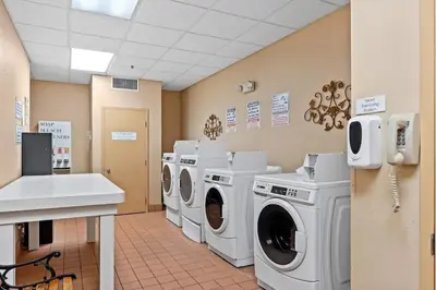 a laundry room with three washing machines and a sink at Apto c/ Vista Piscina – Perto da Disney 1Q in Orlando