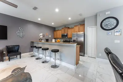 a kitchen with a bar with stools and a clock on the wall at Four Bedroom Private Pool Townhome, near Disney in Kissimmee