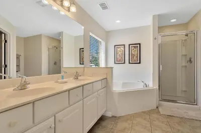 a bathroom with two sinks and a tub and a shower at Spacious 5-Bedroom 4-Bath Pool & Spa Villa in Emerald Island Resort in Kissimmee