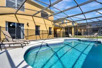 a swimming pool with two chairs and a building at Spacious 5-Bedroom 4-Bath Pool & Spa Villa in Emerald Island Resort in Kissimmee