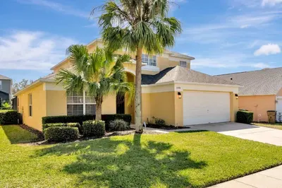 a house with a palm tree and a garage at Spacious 5-Bedroom 4-Bath Pool & Spa Villa in Emerald Island Resort in Kissimmee