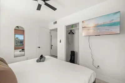 a white bedroom with a bed and a flat screen tv at Game Filled Orlando Retreat with Patio and Grill in Orlando