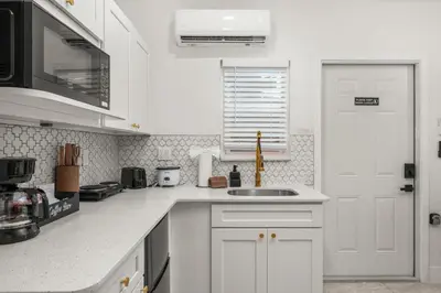 a white kitchen with a sink and a white door at Charming Private Studio Near Everything Orlando in Orlando