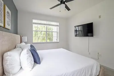 a bedroom with a white bed with a ceiling fan at Landing Stunning 2BD Yoga Studio Gym in Kissimmee