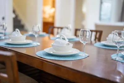 a wooden table with plates and wine glasses on it at Encore Resort luxury house 8 bedrooms, pool and spa in Orlando