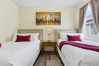 two beds sitting next to each other in a bedroom at Encore Resort luxury house 8 bedrooms, pool and spa in Orlando
