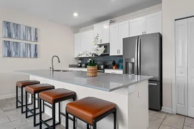 a kitchen with a counter with stools and a refrigerator at Chic Resort Getaway – 15 Min to Disney in Kissimmee