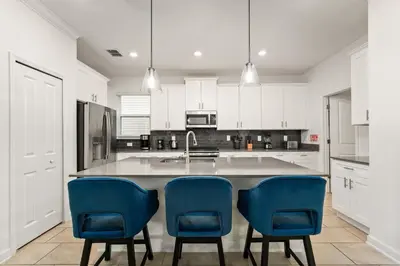 a kitchen with white cabinets and blue chairs at 5BR/5BA Home & Storey Lake Water Park Amenities in Kissimmee
