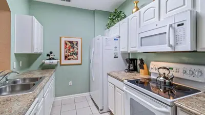 a kitchen with white cabinets and a sink at Windsor Hills Resort in Orlando