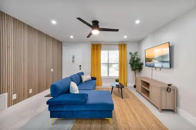 a living room with a blue couch and a tv at Downtown Home with Basketball, Firepit and Just 20 Miles to Disney in Saint Cloud