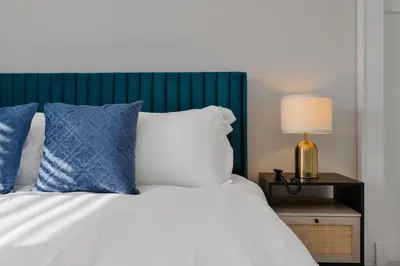 a bed with blue and white pillows and a lamp at Downtown Home with Basketball, Firepit and Just 20 Miles to Disney in Saint Cloud