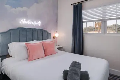 a bedroom with a large white bed with pink pillows at 10 Minutes to Downtown with Jacuzzi, Pool Table, Ping Pong, and BBQ in Orlando