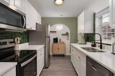 a kitchen with white cabinets and a stainless steel refrigerator at 10 Minutes to Downtown with Jacuzzi, Pool Table, Ping Pong, and BBQ in Orlando