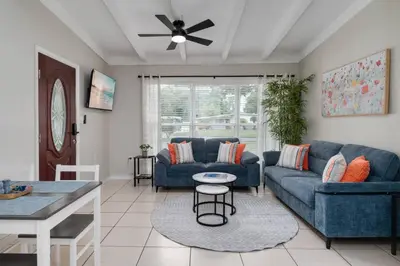 a living room with two blue couches and a ceiling fan at Stylish 2BR Home Near Disney and Universal Orlando in Orlando