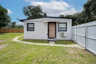 a small white house with a fence at Chic Studio Near Downtown & Theme Parks in Orlando