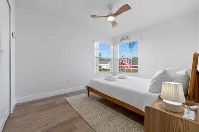 a white bedroom with a bed and a window at Bright Ground Floor Condo Minutes to Parks in Kissimmee