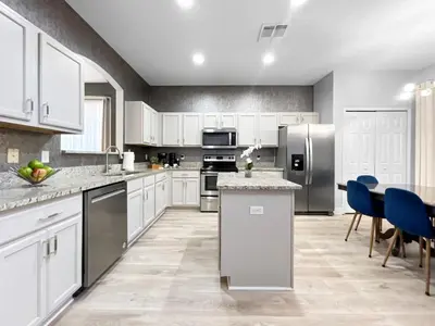 a large kitchen with white cabinets and a table at NEW Luxury 7BR Villa 4 Mi to Disney Pool & Spa in Kissimmee