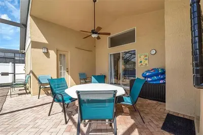 a patio with a table and chairs and a ceiling fan at 5BR 4BA Near Disney, Pool, Sauna, Pets Allowed in Kissimmee