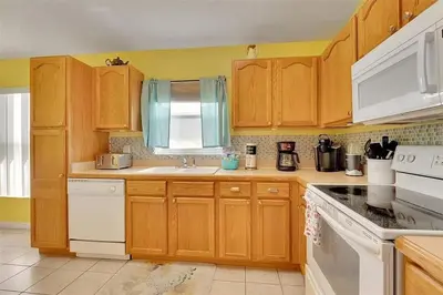 a kitchen with wooden cabinets and white appliances at 5BR 4BA Near Disney, Pool, Sauna, Pets Allowed in Kissimmee