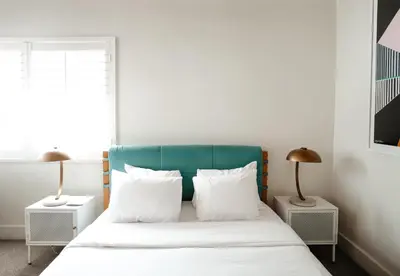 a bedroom with a bed with white sheets and two lamps at Suites by The Wellborn in Orlando