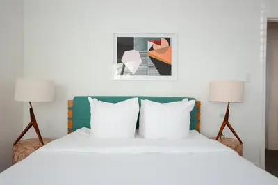 a bedroom with a large white bed with two lamps at Suites by The Wellborn in Orlando