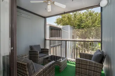 a screened in porch with two chairs and a table at Condo with Pool, Gym, Golf, Jacuzzi and Game Areas in Orlando