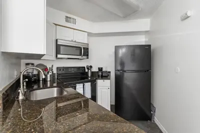 a kitchen with a stainless steel refrigerator and a sink at Cozy Apt with Pool, Hot Tub, Golf, Near Downtown in Orlando