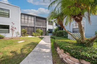 a sidewalk in front of a building with a palm tree at Cozy Golf Condo with 3 Pools, Gym and Just 15 Minutes to Airport in Orlando