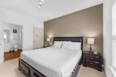 a bedroom with a large bed with white sheets at 8925 Resort 4BR Townhouse by Disney World Orlando in Kissimmee