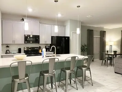a kitchen with white cabinets and a island with chairs at 4263PD-New Listing- 5 bed/4 bath-Private Pool in Kissimmee