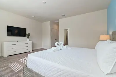 a white bedroom with a white bed and a tv at New townhouse in Clermont -Orlando area in Orlando