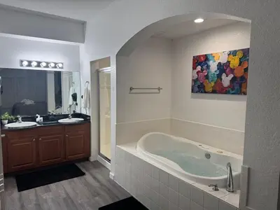 a bathroom with a tub and two sinks and a painting at Magical Condo 3 bedroom in Orlando