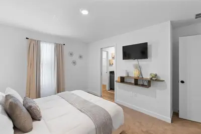 a white bedroom with a bed and a flat screen tv at Elegant Home near Disney - pool - free parking in Kissimmee