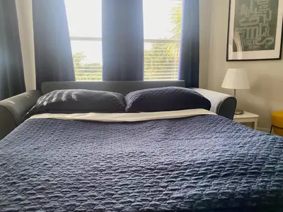 a bed with a blue comforter in front of a window at Sea World Orlando Apts Parks Convention Centre in Orlando